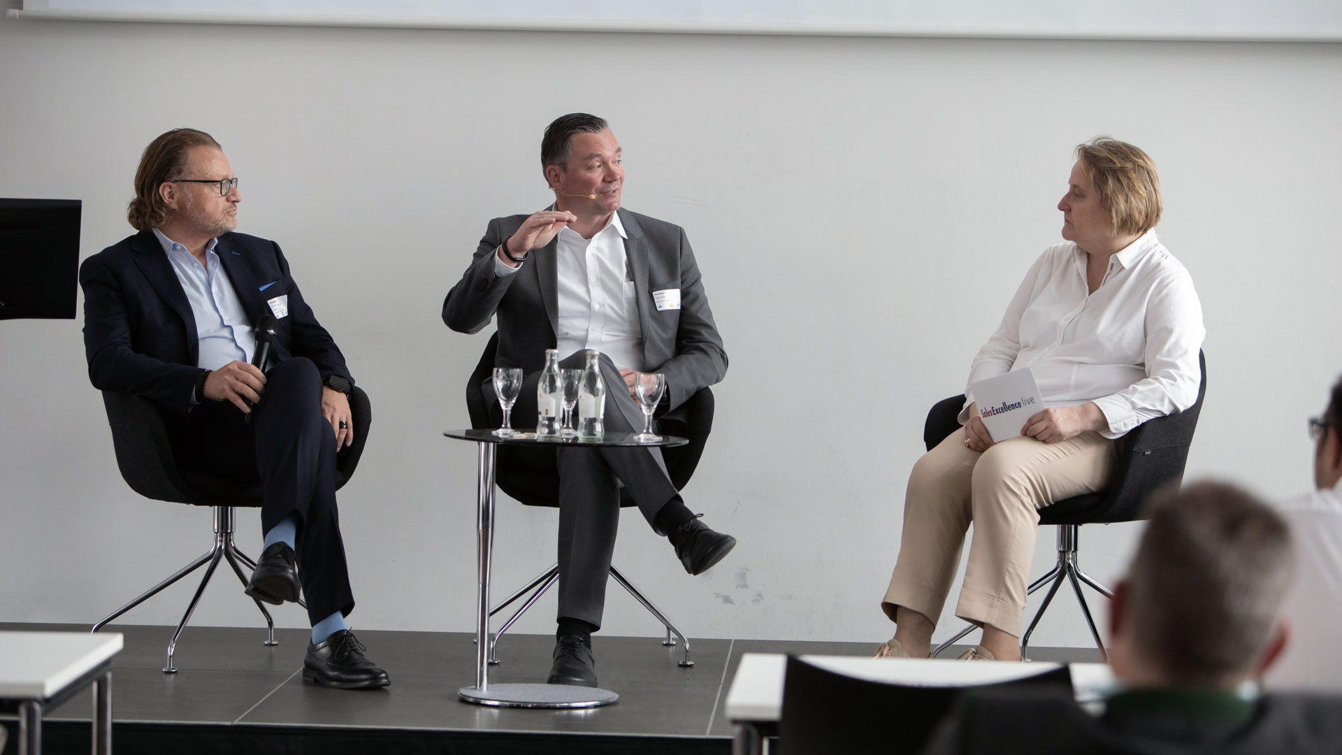 Podiumsdiskussion mit drei Diskutanten vor Publikum.